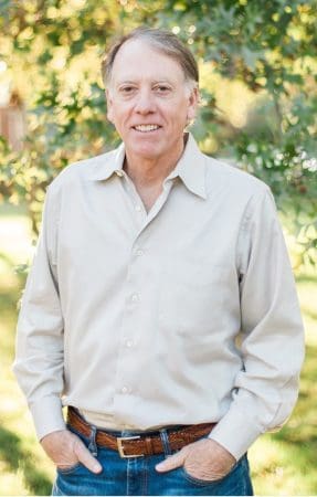 A photo of Dr. Reynolds outdoors, smiling beneath a tree.